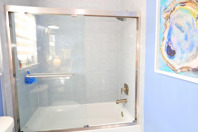 bathroom featuring toilet and combined bath / shower with glass door