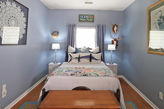 bedroom with visible vents, baseboards, and wood finished floors