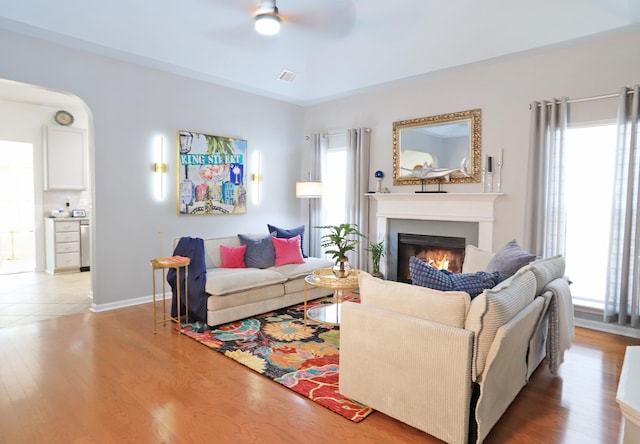 living area with a lit fireplace, a wealth of natural light, and wood finished floors