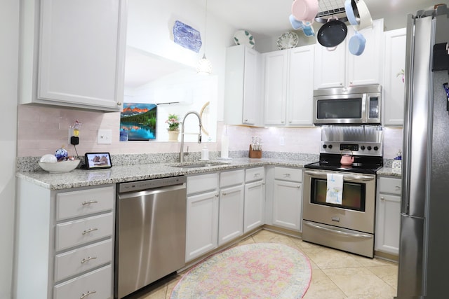 kitchen with appliances with stainless steel finishes, a sink, light stone counters, and tasteful backsplash