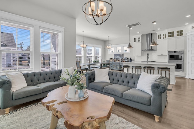 living area with recessed lighting, visible vents, a notable chandelier, and light wood finished floors