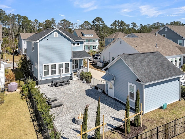 back of house with a shingled roof, a residential view, an outdoor fire pit, a fenced backyard, and a patio area