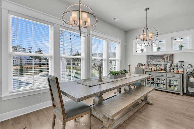 dining space with light wood finished floors, visible vents, baseboards, and an inviting chandelier