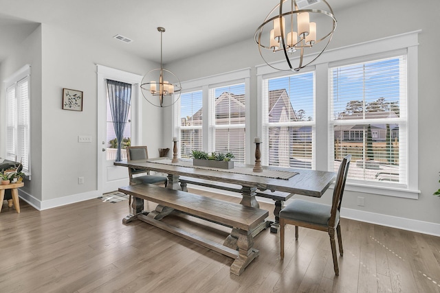 dining area with visible vents, a notable chandelier, wood finished floors, and baseboards