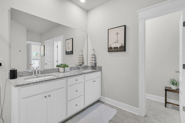 bathroom featuring double vanity, baseboards, and a sink