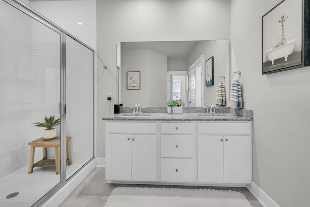 bathroom with a sink, baseboards, a stall shower, and double vanity