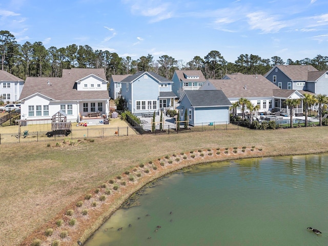 back of property featuring a yard, a fenced backyard, a residential view, and a water view