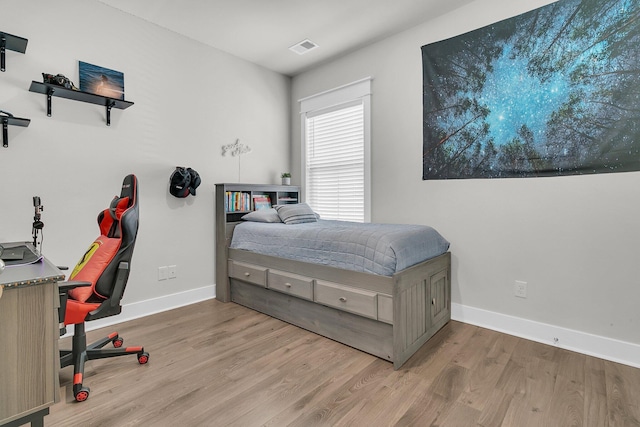 bedroom with visible vents, baseboards, and wood finished floors