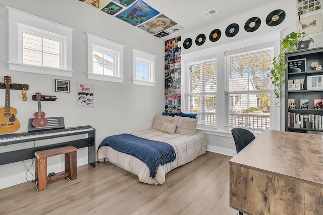 bedroom featuring visible vents, multiple windows, light wood-type flooring, and baseboards