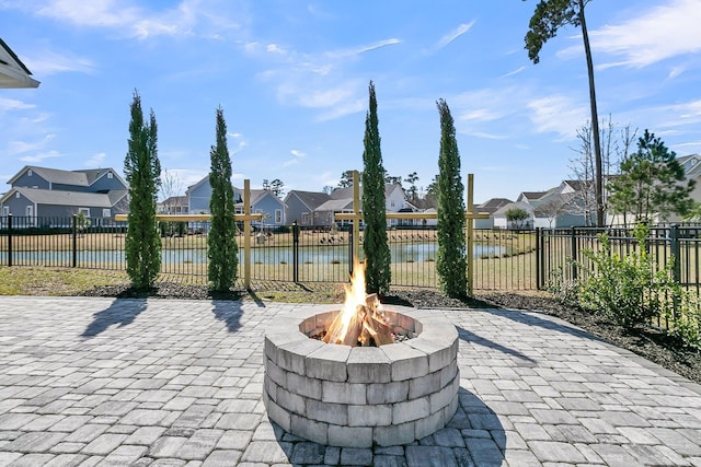 view of patio featuring fence, a residential view, a water view, and an outdoor fire pit