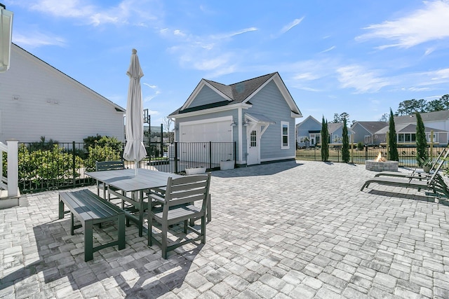 view of patio featuring a fire pit, fence, a garage, an outbuilding, and outdoor dining space