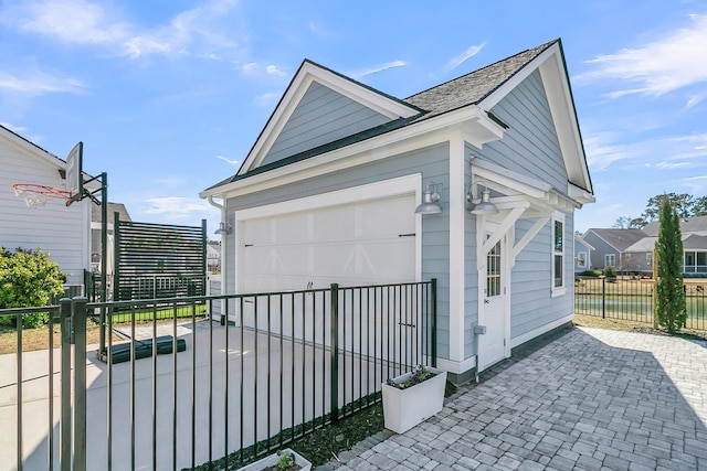 view of home's exterior featuring a garage, an outdoor structure, driveway, and fence