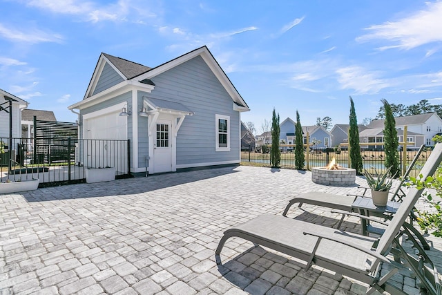 exterior space with a fire pit, fence, a residential view, a garage, and a patio area