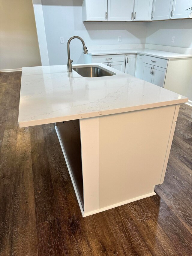 kitchen featuring light stone countertops, dark hardwood / wood-style floors, sink, and white cabinetry