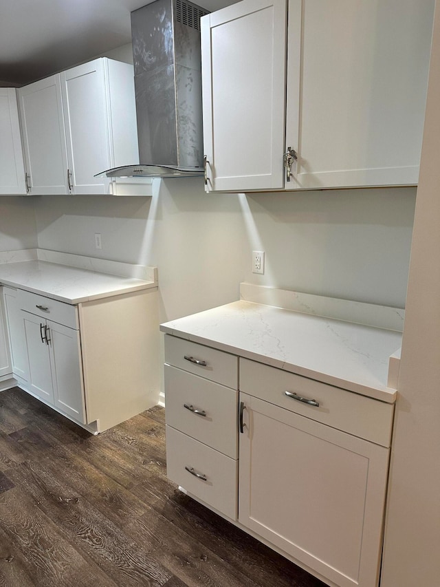 kitchen featuring wall chimney exhaust hood, light stone countertops, dark hardwood / wood-style flooring, and white cabinets