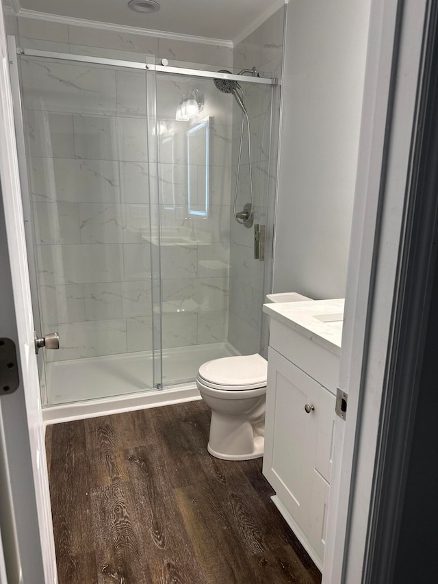 bathroom with toilet, hardwood / wood-style floors, an enclosed shower, ornamental molding, and vanity