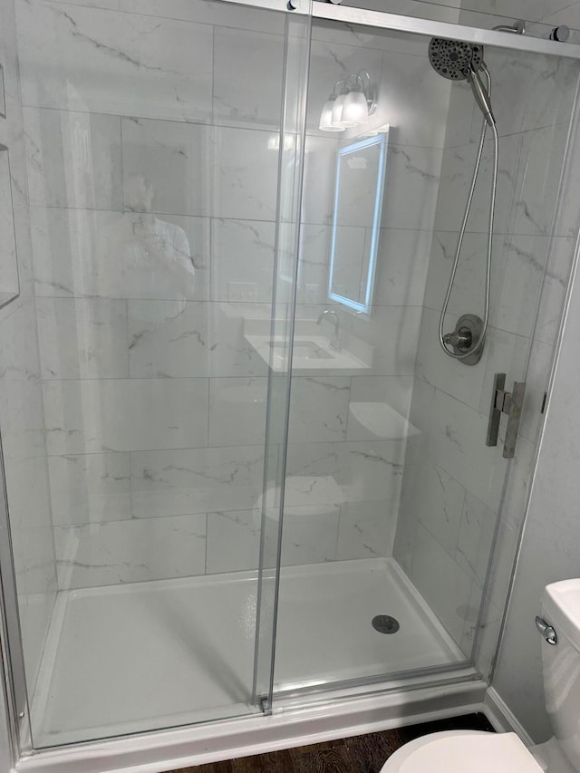 bathroom featuring toilet and a shower with shower door