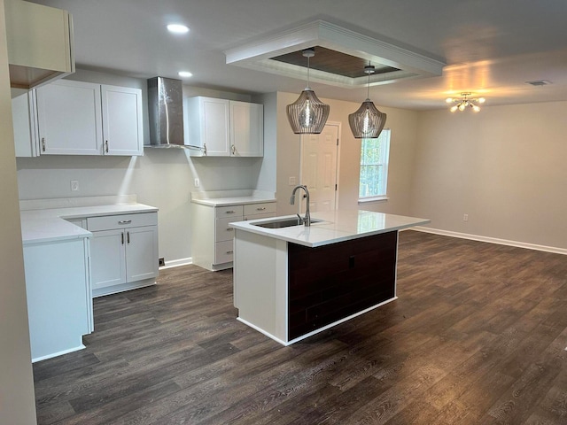 kitchen with white cabinets, decorative light fixtures, sink, and wall chimney range hood