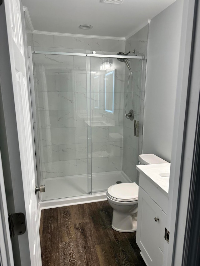 bathroom featuring hardwood / wood-style floors, vanity, a shower with door, crown molding, and toilet