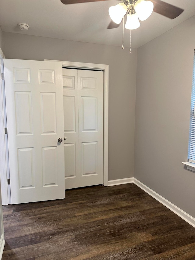 unfurnished bedroom featuring dark wood-type flooring, a closet, and ceiling fan