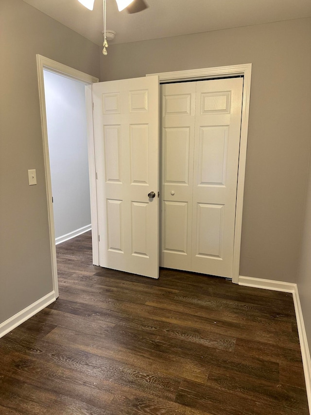 unfurnished bedroom featuring ceiling fan, a closet, and dark hardwood / wood-style flooring