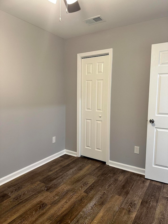 unfurnished bedroom with a closet, dark hardwood / wood-style floors, and ceiling fan