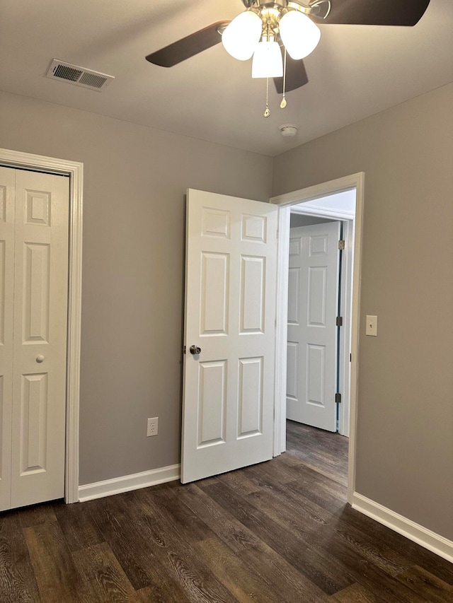 unfurnished bedroom featuring ceiling fan, a closet, and dark wood-type flooring