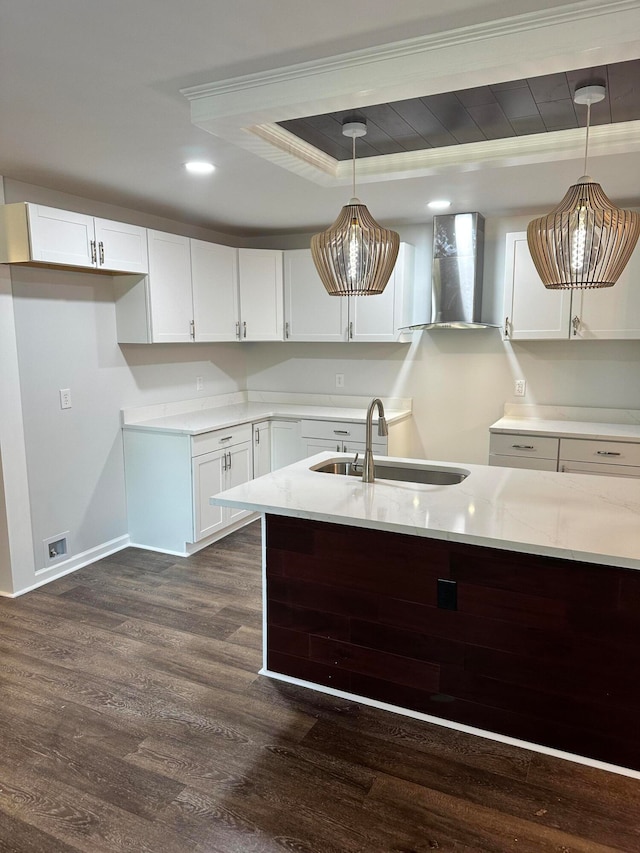 kitchen with pendant lighting, white cabinets, sink, wall chimney exhaust hood, and dark wood-type flooring