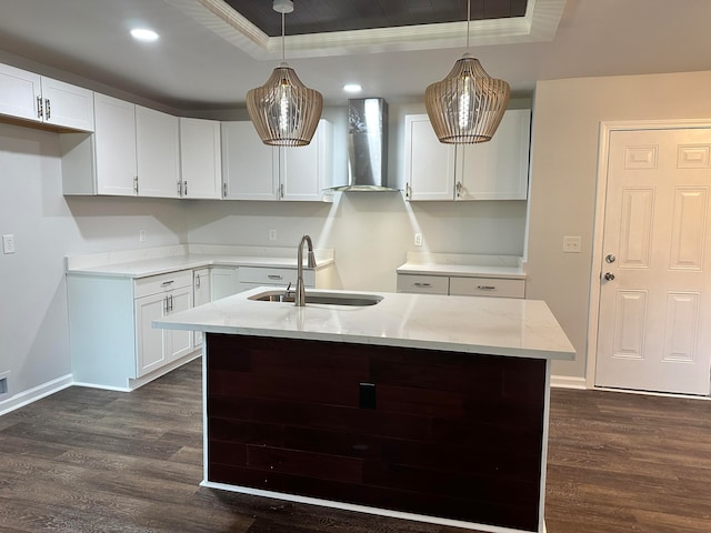 kitchen with dark hardwood / wood-style flooring, hanging light fixtures, sink, and wall chimney range hood