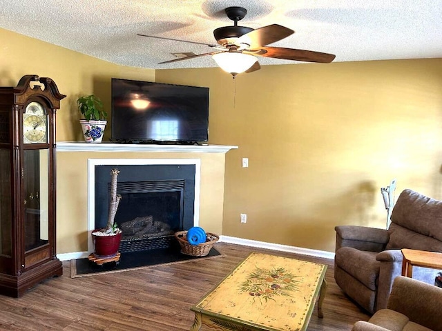 living room featuring ceiling fan, dark wood-type flooring, and a textured ceiling