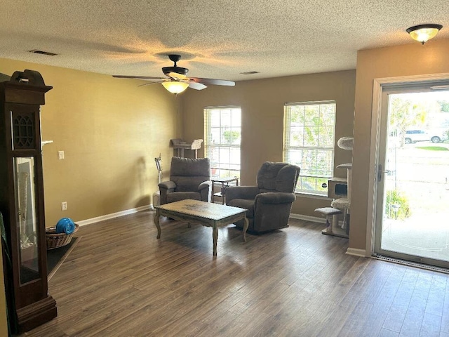 living area with a textured ceiling, dark hardwood / wood-style floors, and ceiling fan