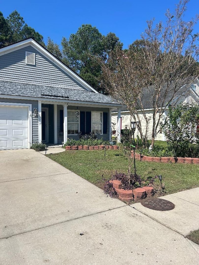 view of front of home featuring covered porch, a garage, and a front yard