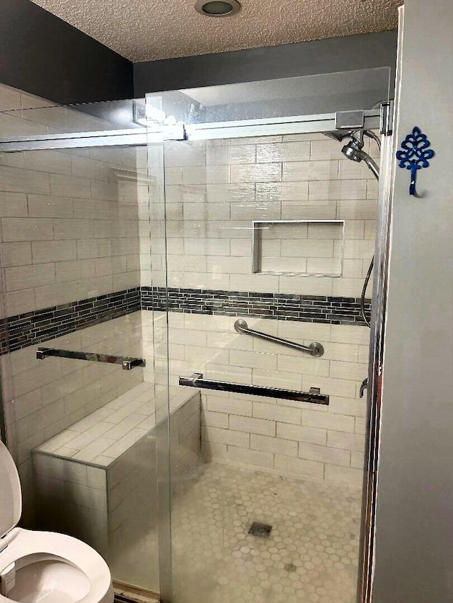 bathroom featuring toilet, a textured ceiling, and walk in shower