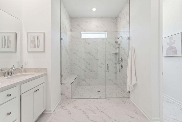 bathroom featuring marble finish floor, a marble finish shower, vanity, and baseboards