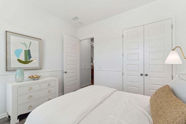 bedroom with visible vents, a closet, and wainscoting