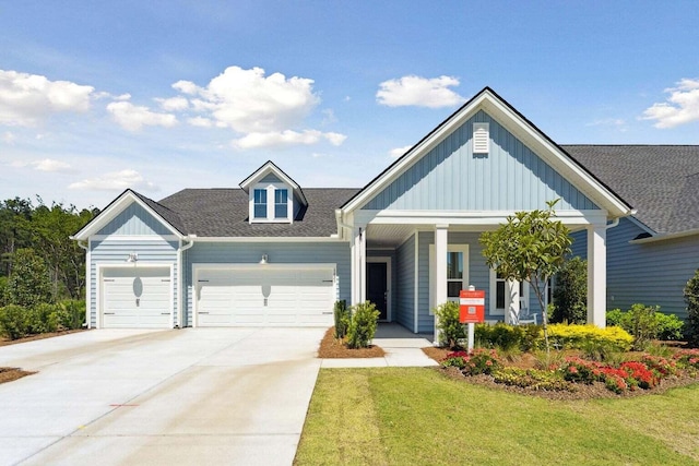 view of front facade featuring a shingled roof, an attached garage, board and batten siding, driveway, and a front lawn