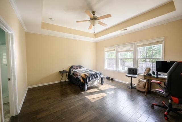 bedroom featuring ceiling fan, dark wood-type flooring, ornamental molding, and a raised ceiling