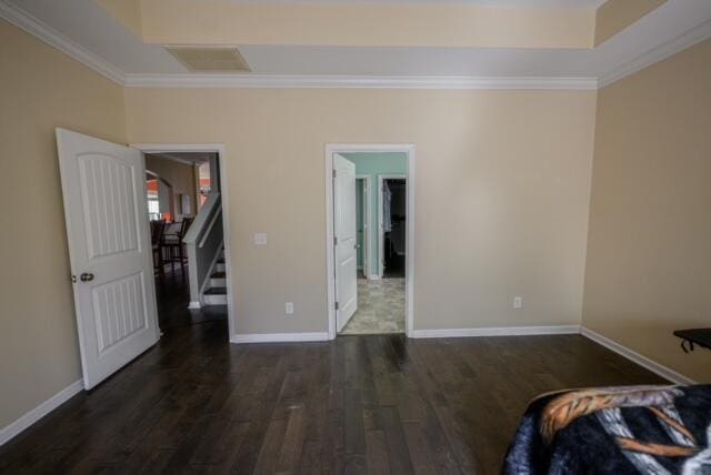 unfurnished bedroom with dark hardwood / wood-style floors, crown molding, and a raised ceiling