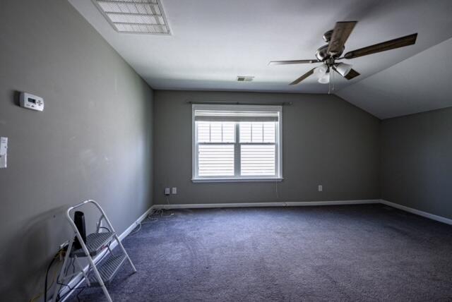 bonus room with dark colored carpet, lofted ceiling, and ceiling fan