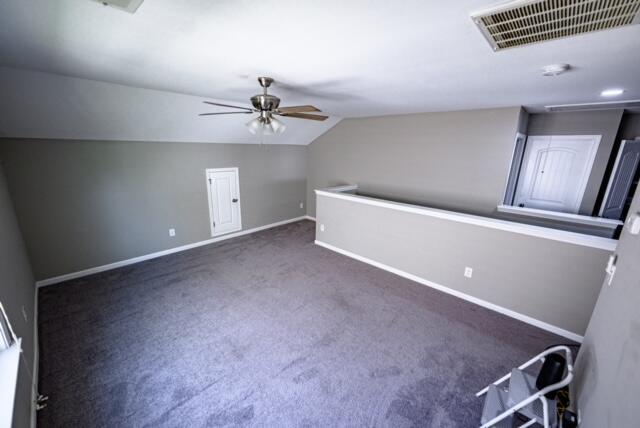 additional living space featuring ceiling fan, vaulted ceiling, and dark colored carpet