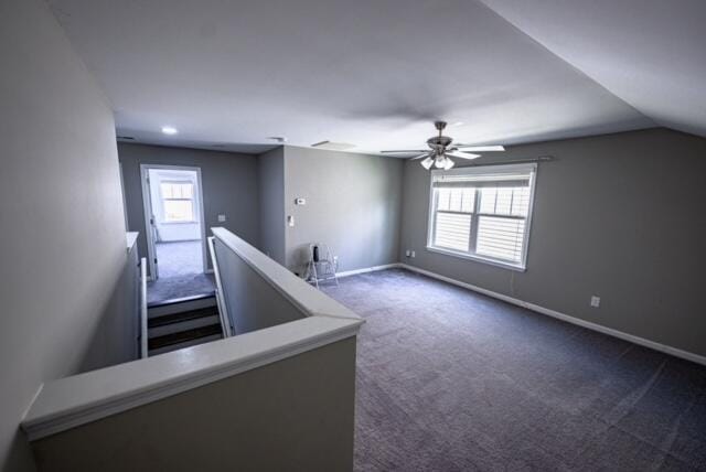 bonus room with vaulted ceiling, dark colored carpet, plenty of natural light, and ceiling fan