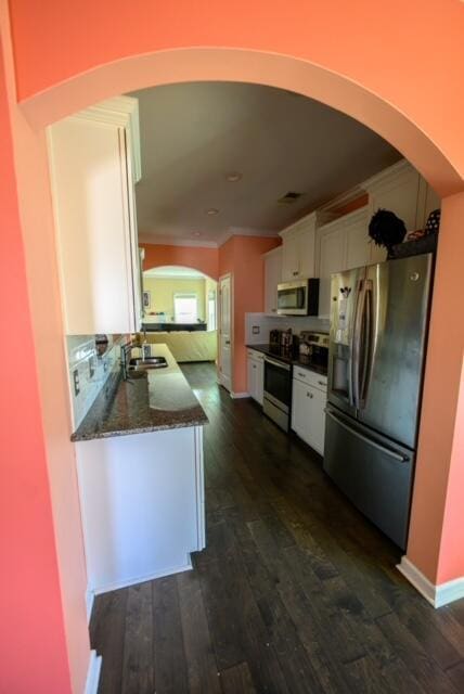 kitchen featuring white cabinetry, stainless steel appliances, dark wood-type flooring, stone counters, and sink