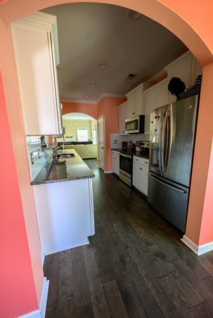 kitchen with appliances with stainless steel finishes, dark hardwood / wood-style flooring, stone countertops, and white cabinetry