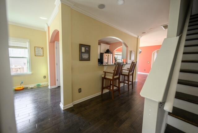 hall with dark wood-type flooring and crown molding