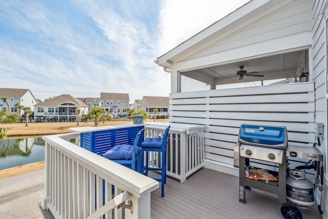 deck featuring a water view, a grill, a residential view, and a ceiling fan