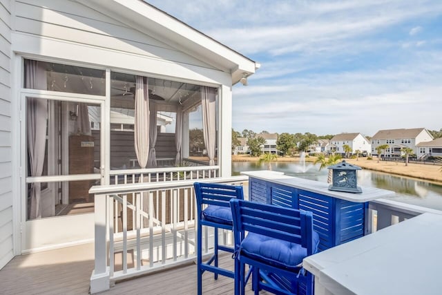 wooden deck featuring a residential view, a sunroom, and a water view