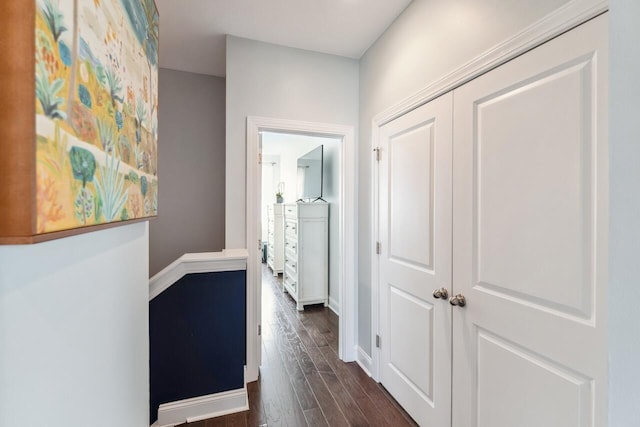 hallway featuring dark wood-type flooring and baseboards