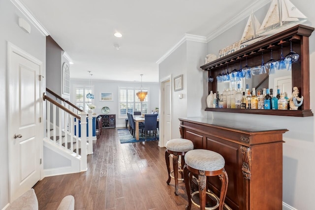 bar featuring a dry bar, baseboards, dark wood finished floors, ornamental molding, and stairs