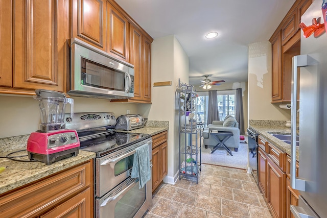 851 Sandlake Dr Unit D, Mount Pleasant, SC 29464 - kitchen with stainless steel appliances, brown cabinets, ceiling fan, light stone countertops, and recessed lighting