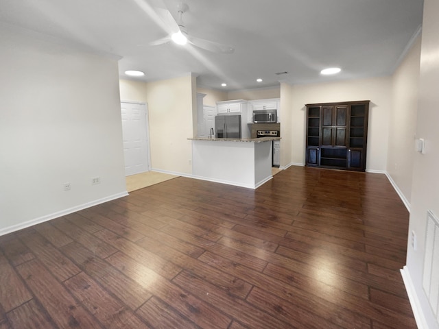 unfurnished living room featuring ceiling fan, sink, and dark hardwood / wood-style floors